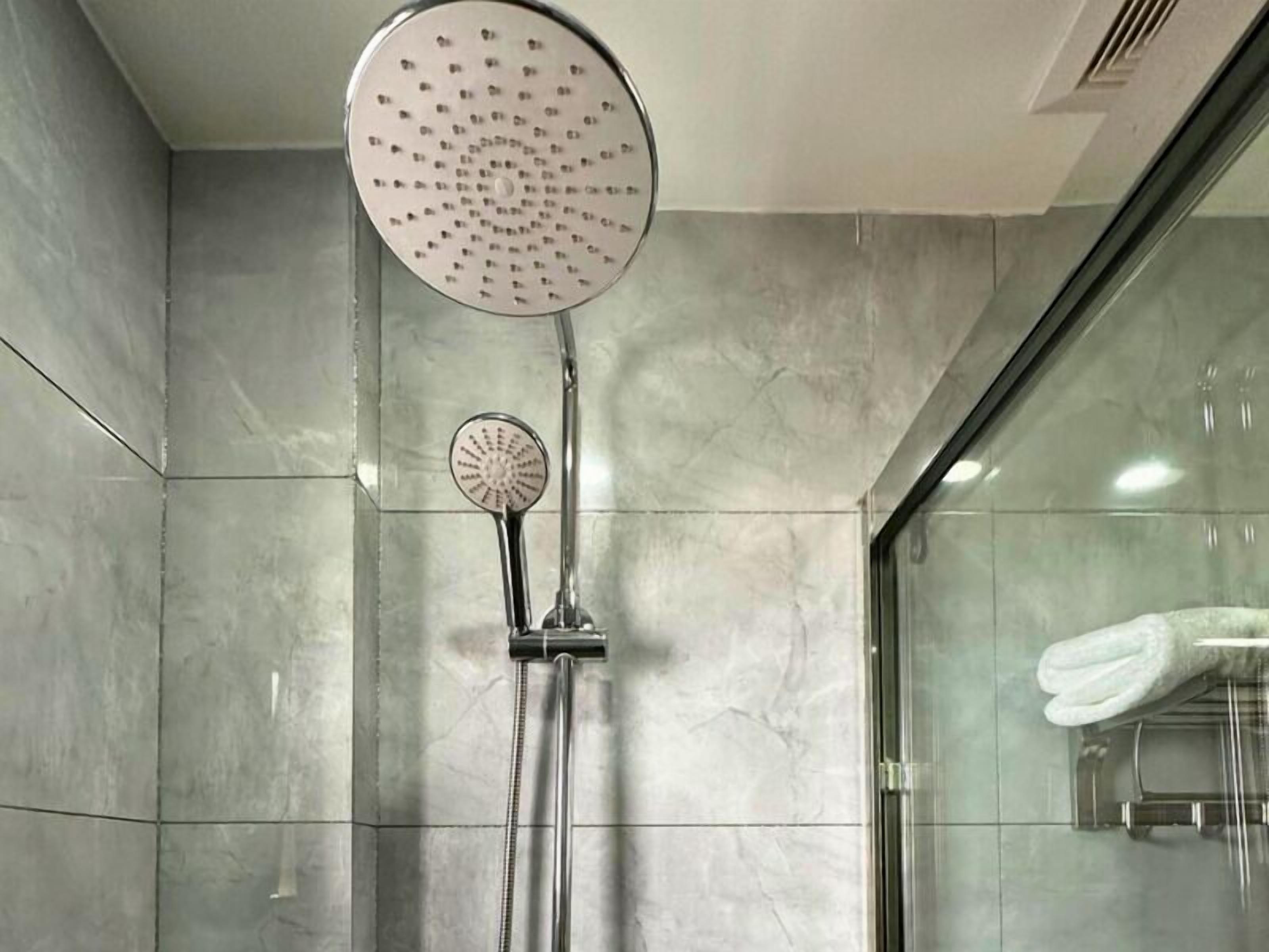 Un baño moderno con cabina de ducha de vidrio, ducha de mano y panel de control en la pared.