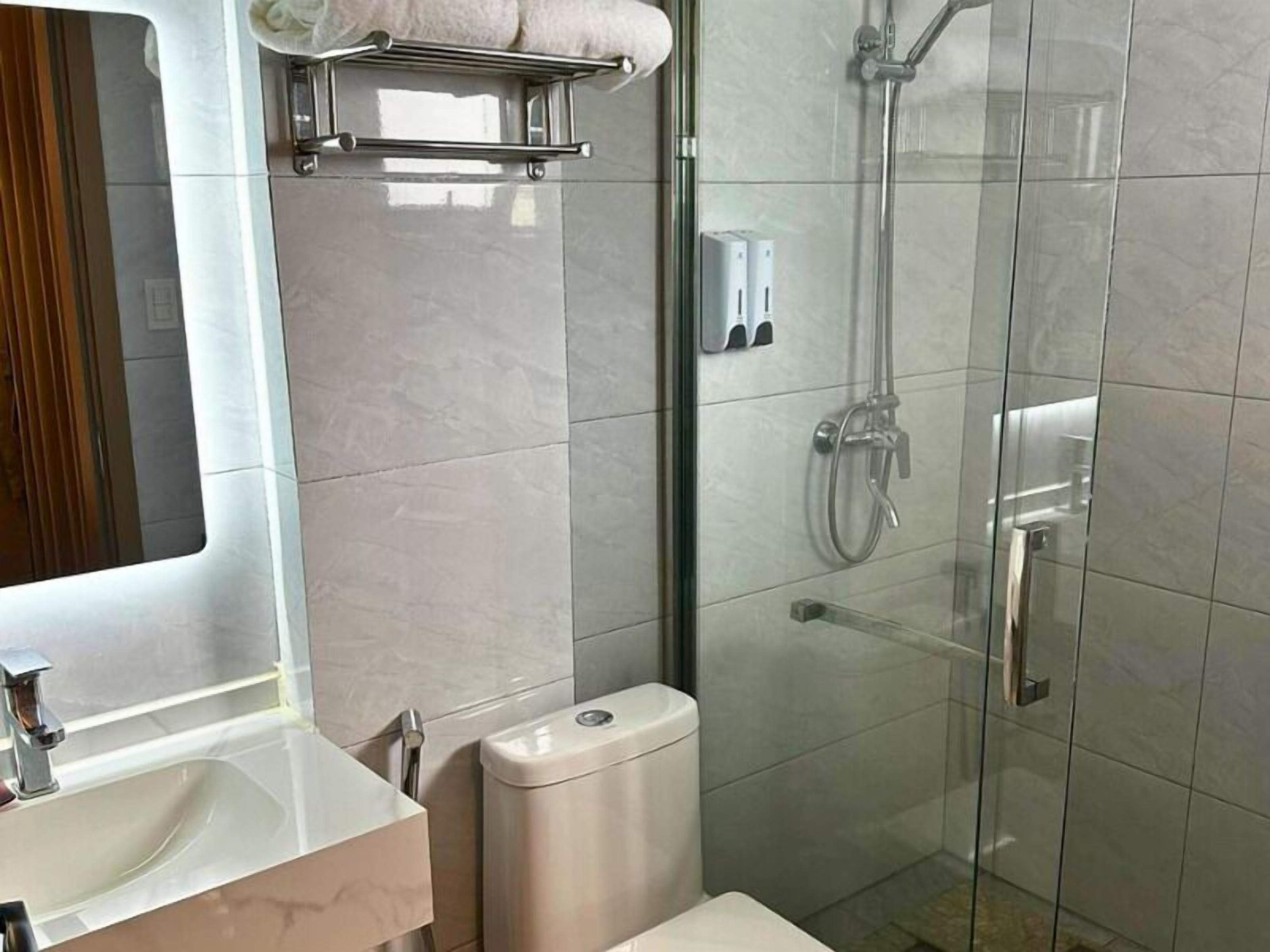 Ein modernes Badezimmer mit Duschkabine aus Glas, Toilette, Waschbecken und Handtuchhalter.