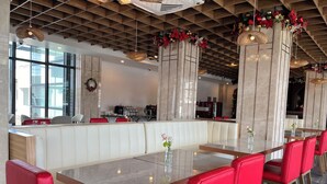 Un restaurant doté d’un long comptoir, de chaises rouges et d’un plafond au design moderne.