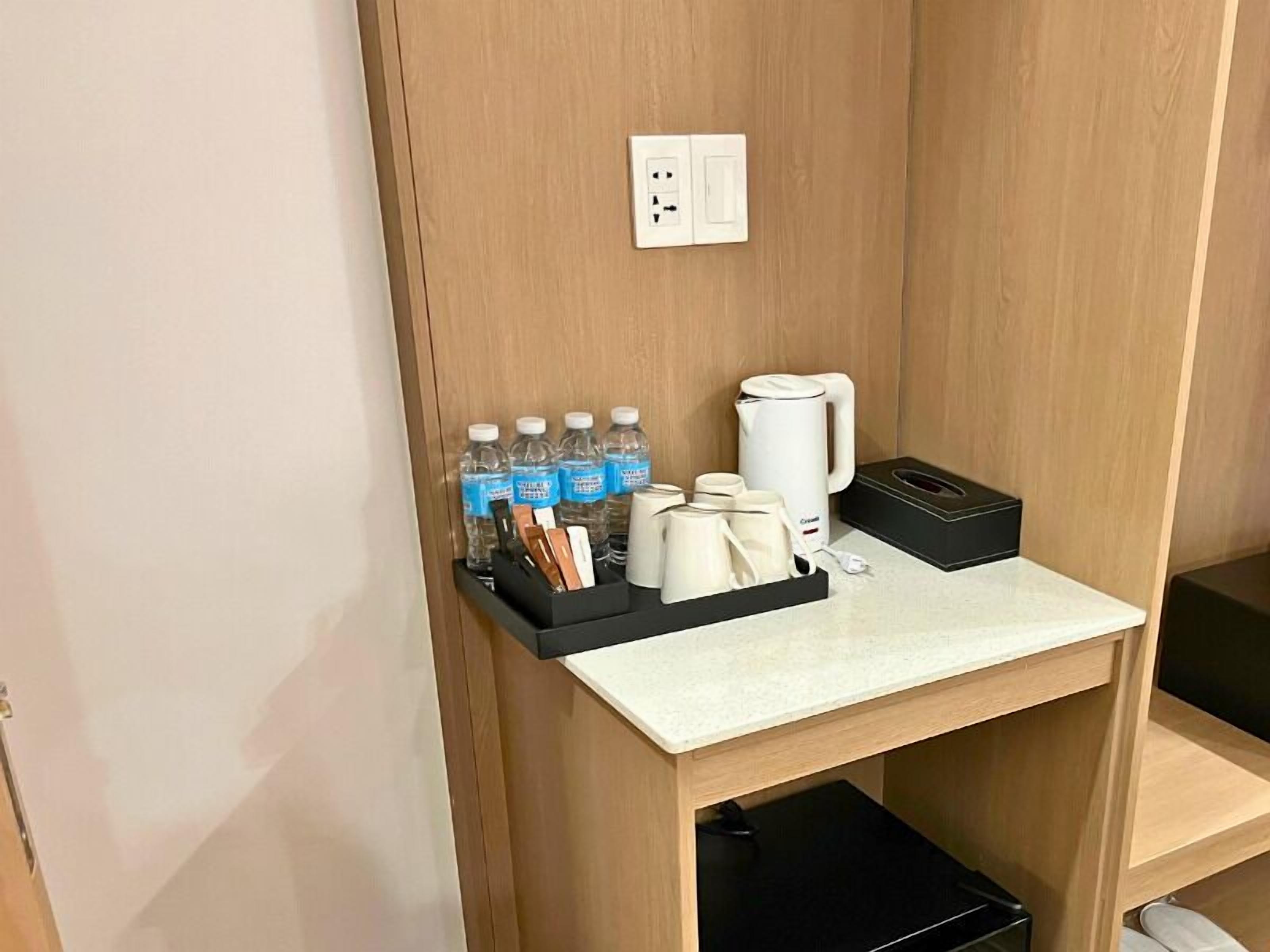 A small kitchenette with a countertop, a coffee maker, a kettle, and a water bottle holder.