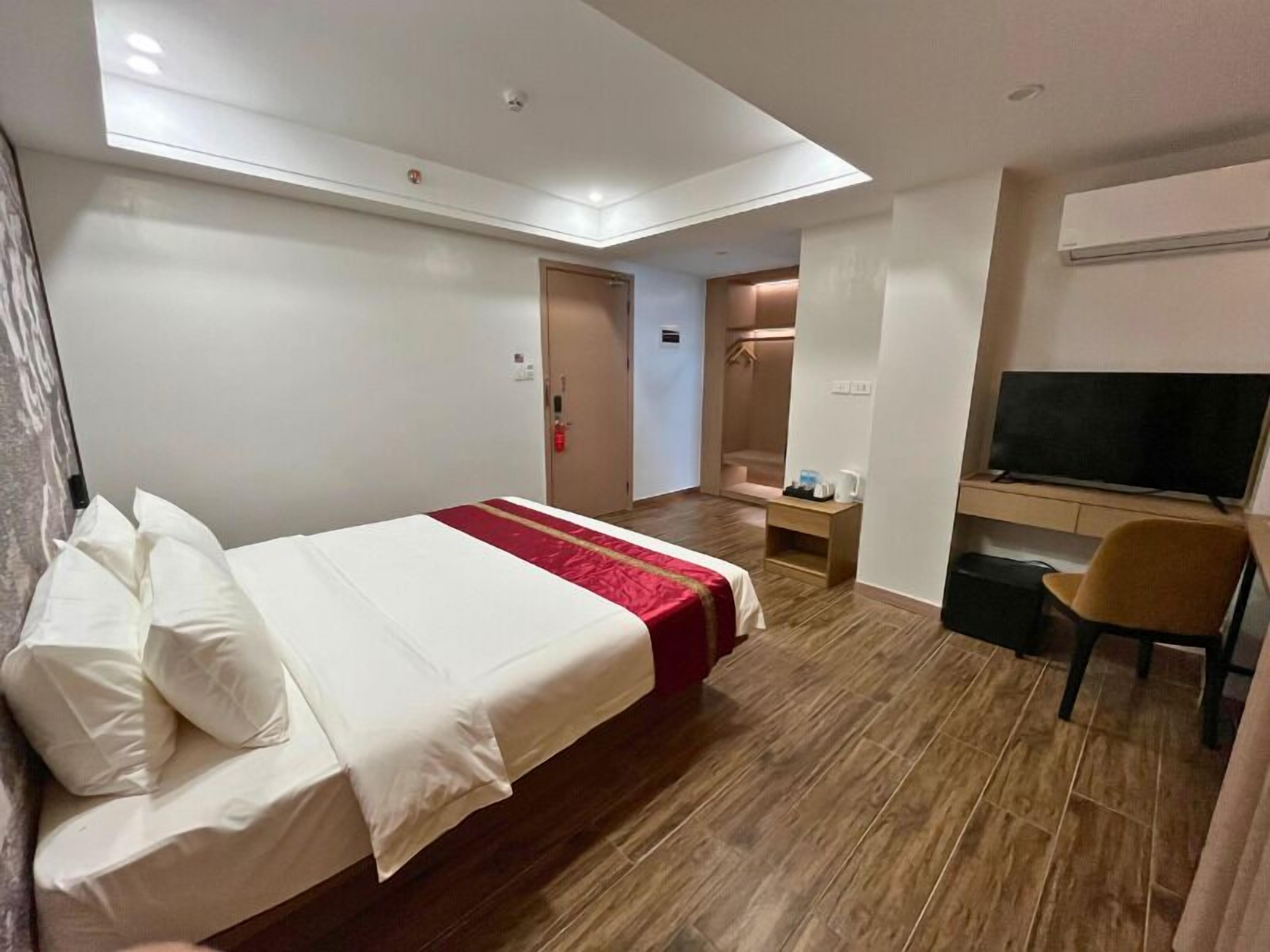 A hotel room with a bed, a TV, a desk, and a shower area.