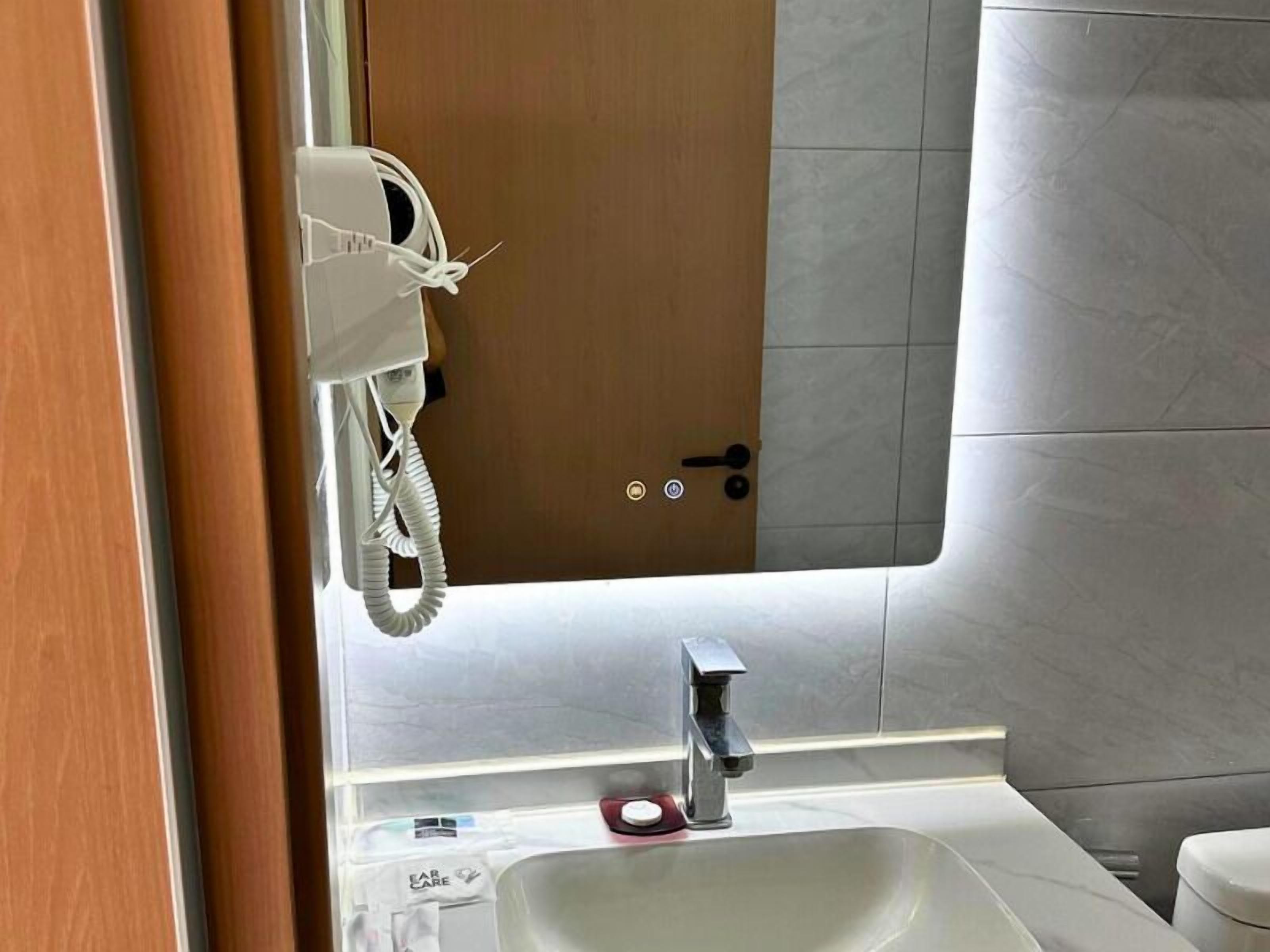 A bathroom with a white sink, a mirror, and a telephone mounted on the wall.