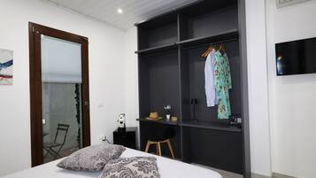 Un dormitorio con cama, armario, escritorio y televisor.