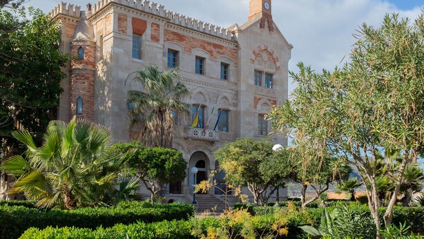 A historic building with a clock tower, arched windows, and a central entrance.