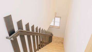 Una escalera de madera con barandilla de metal que lleva a una ventana.