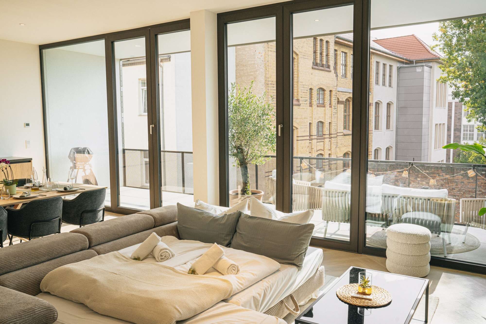 A modern hotel room with a large bed, a desk, and a balcony with a view of the city.