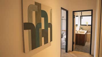 Ein Flur mit einem modernen, abstrakten Gemälde an der Wand, der zu einem Badezimmer mit Waschbecken und einer Topfpflanze führt.