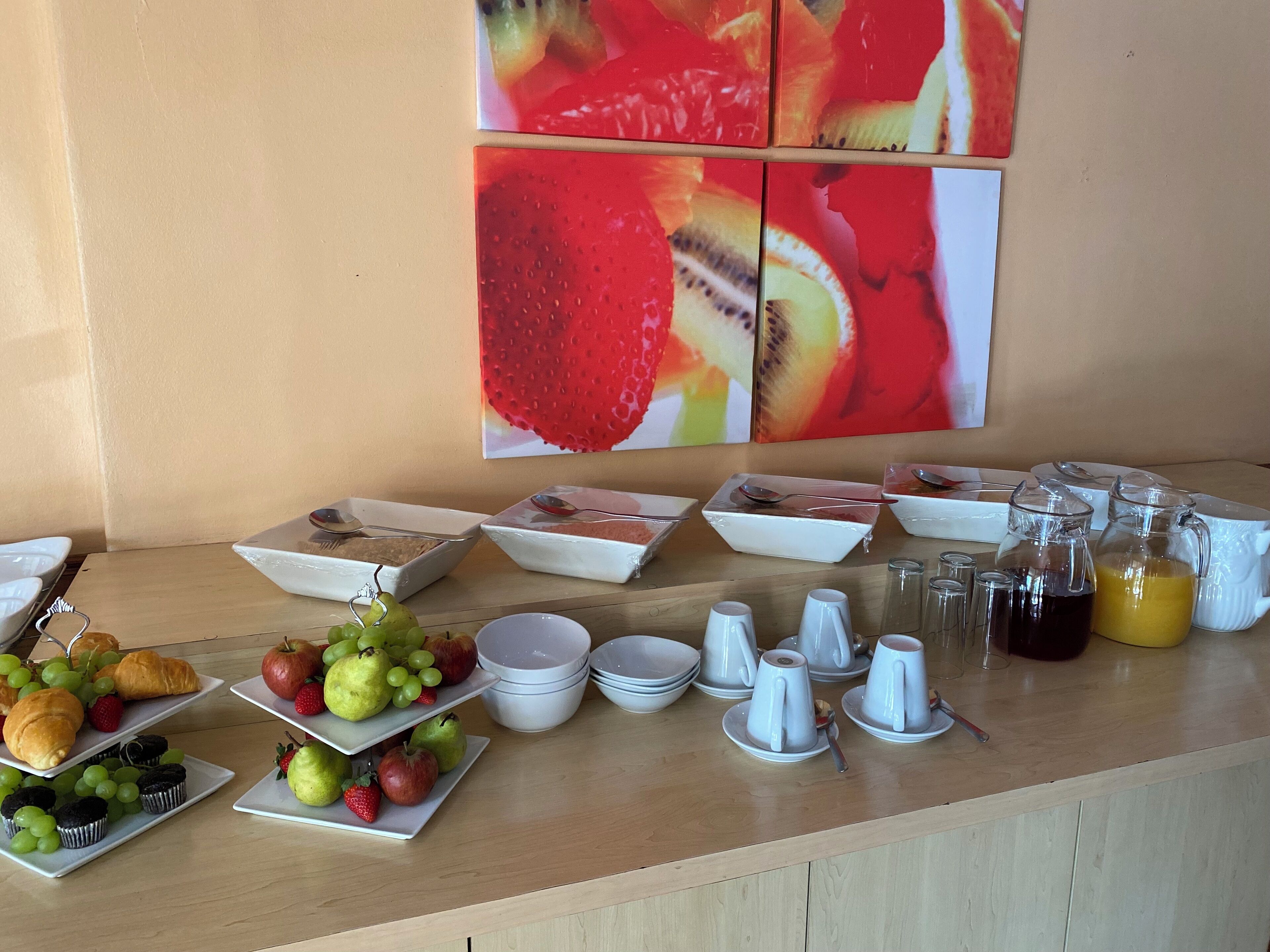 A breakfast buffet with various fruits, pastries, and beverages.