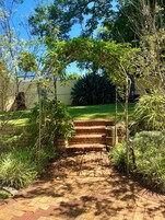 Un camino de ladrillo que lleva a una casa con jardín y un cielo azul despejado.