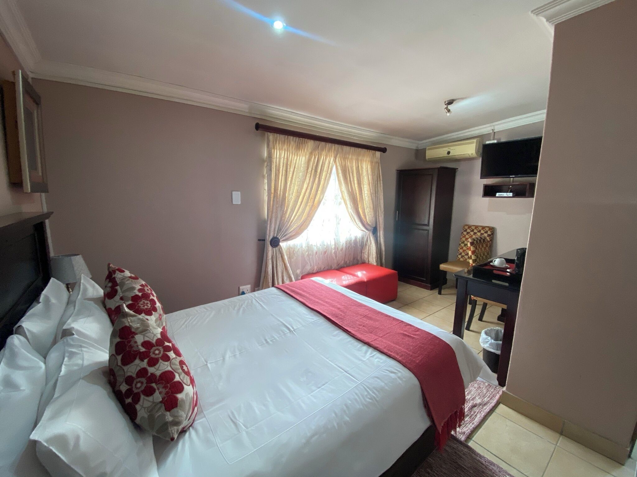 A hotel room with a bed, a desk, a television, and a wardrobe.