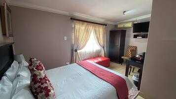A hotel room with a bed, a desk, a television, and a wardrobe.