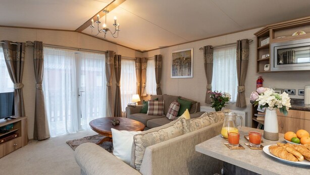 Een gezellige woonkamer met een bank, een salontafel en een eethoek, gedekt voor het ontbijt.