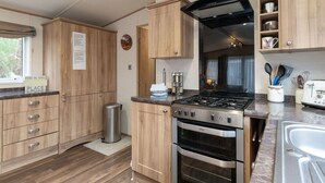 Een moderne keuken met houten kastjes, een gasfornuis, een oven en een spoelbak.