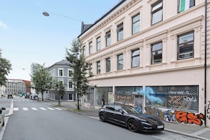 A street with a parked car and buildings with graffiti.