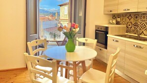 Una piccola cucina con zona pranzo, vista su edifici e un balcone fiorito.
