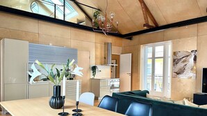 A modern kitchen with a wooden countertop, a dining table with chairs, and a large window. - Unique Design House in Downtown Oslo (Oslo)