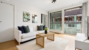 Ein modernes Wohnzimmer mit einem weißen Sofa, zwei Beistelltischen und einem Kunstwerk an der Wand.