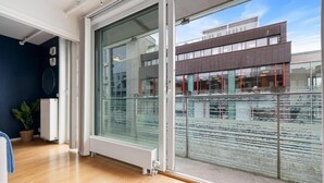 Ein modernes Zimmer mit einer großen Schiebeglasdoor, die auf einen Balkon führt, einem Heizkörper und einer Topfpflanze.