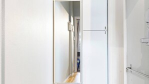 Un pasillo con piso de madera, paredes blancas y una puerta que da a otra habitación.