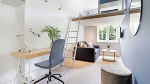 Un dormitorio compacto con una litera, un escritorio con silla, una mesita redonda y una planta en maceta.