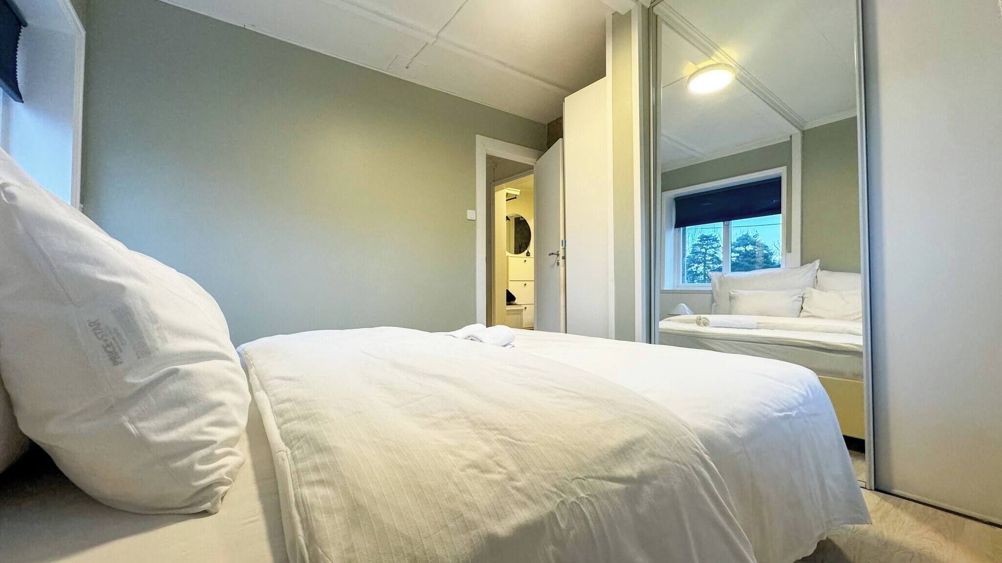 Ein Hotelzimmer mit einem Bett, einem großen Fenster und einem Spiegel, der den Raum widergibt.