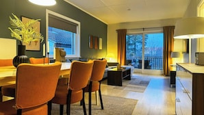 A modern living room with a dining area, large windows, and a balcony. - Cozy 2BR Apartment With Parking (Oslo)