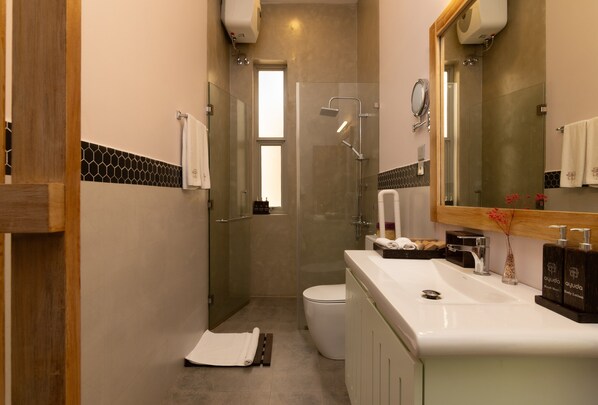 A bathroom with a glass-enclosed shower, a white sink, and a large mirror.