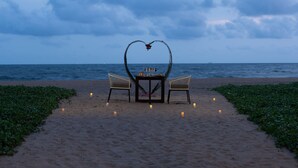 A beach setting with a heart-shaped arrangement of chairs and a table, a hammock, and candles on the sand. - Ayuda Sanctuary Boutique Negombo (Negombo)