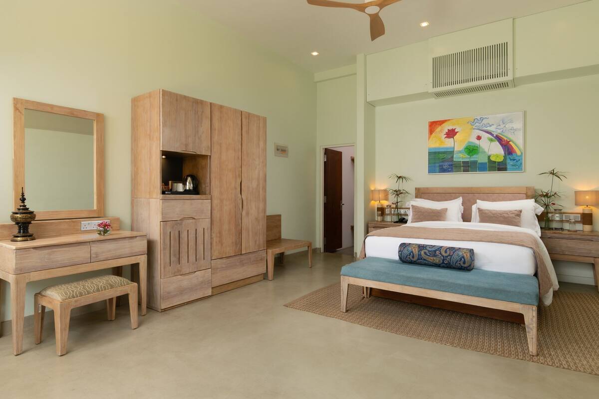 Une chambre à coucher comprenant un lit, une table de chevet, une armoire en bois et un miroir.