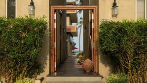 A pathway leading to a building with a wooden frame entrance, surrounded by lush greenery and a view of the sea. - Ayuda Sanctuary Boutique Negombo (Negombo)