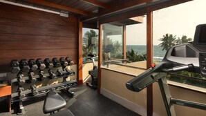 A gym with weight machines, a treadmill, and a view of the ocean. - Ayuda Sanctuary Boutique Negombo (Negombo)
