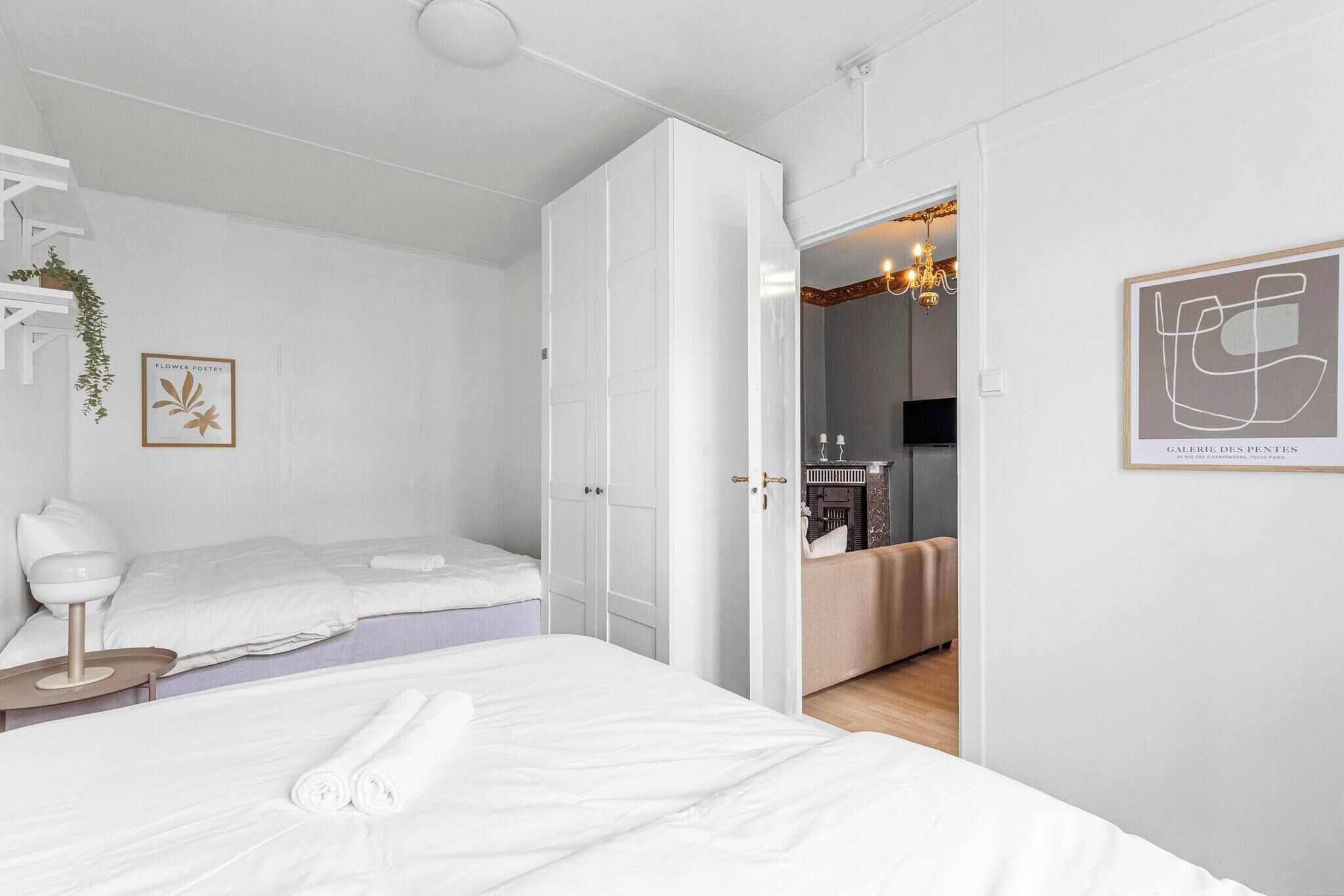 A modern hotel room with a large bed, a bedside table, a chair, and a wardrobe.