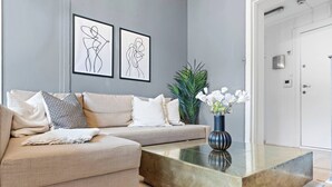 A modern living room with a beige sofa, a glass coffee table, and two abstract art pieces on the wall. - Big and Bright Apartment in the Center (Oslo)
