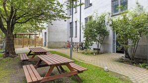 A courtyard with picnic tables, bicycles, and a building with large windows. - Big and Bright Apartment in the Center (Oslo)