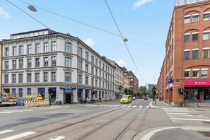 A street view with tram tracks, a tram, and buildings with commercial establishments. - Big and Bright Apartment in the Center (Oslo)