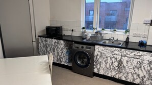 A compact kitchen with a washing machine, a microwave, and a sink. - 1br-sleeps4-35mintocentrallondon-40mintoheathrow (London)