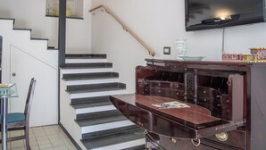 A staircase with a handrail, a flat-screen TV mounted above, and a wooden cabinet with drawers. - Camula Inn (Catania)