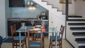 A modern kitchen with a dining area, featuring a glass table, wooden chairs, and a staircase. - Camula Inn (Catania)