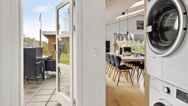 Et moderne køkken med en stor vaskemaskine, et spiseområde med stole og udsigt til det fri.