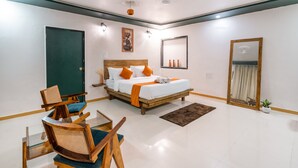 A bedroom with a bed, two chairs, a small table, a mirror, and a door. - Moustache Daman (Daman)