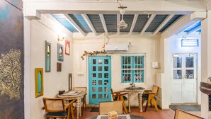A room with a blue door, wooden furniture, and a ceiling fan. - Moustache Daman (Daman)