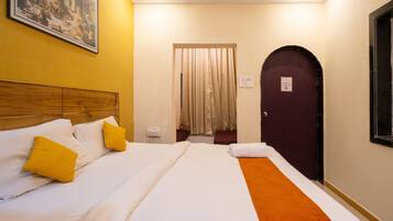 A hotel room with a bed, a wooden headboard, a painting on the wall, a door, and a window.