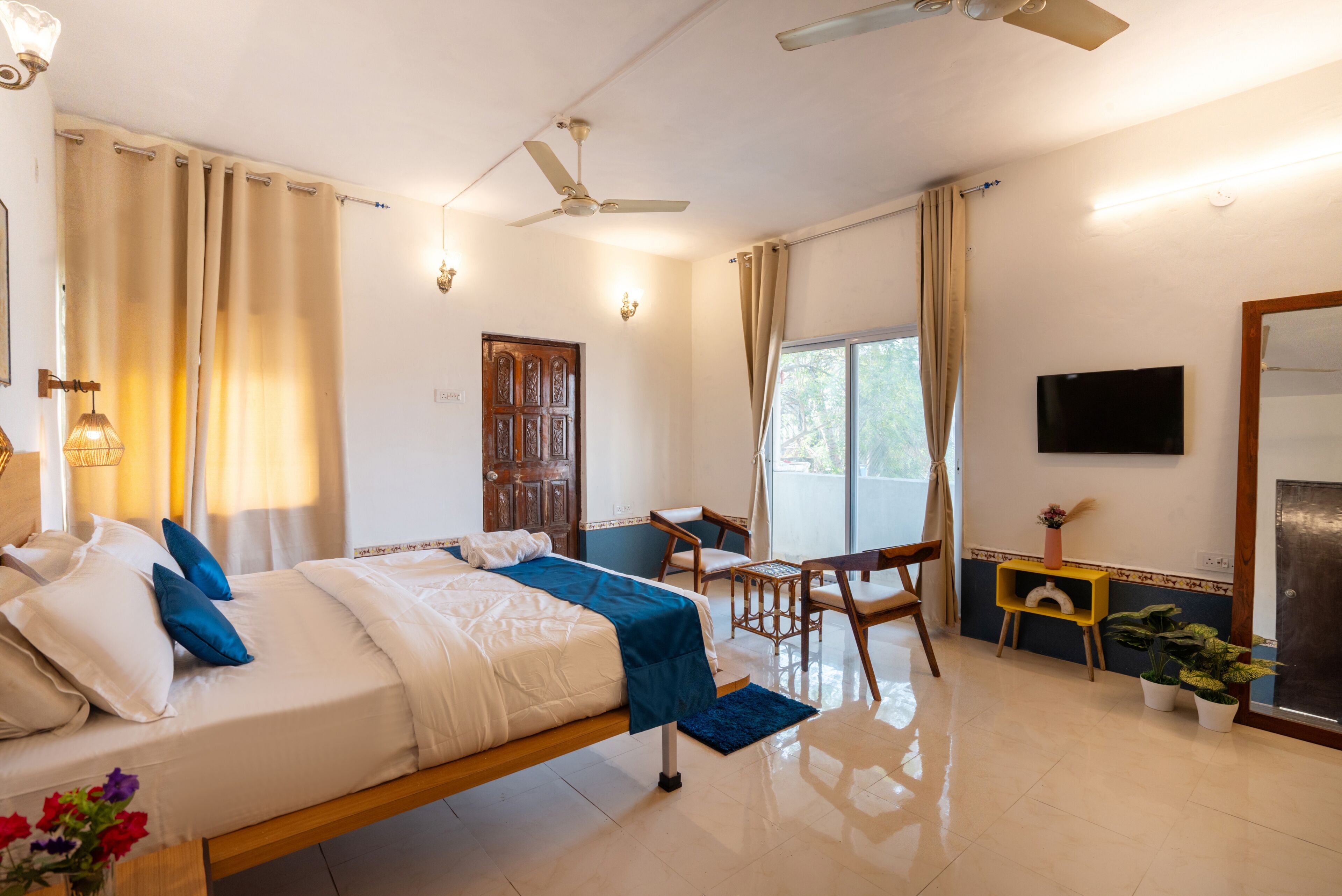 A hotel room with a bed, a desk, a chair, a TV, and a ceiling fan.