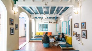 A cozy interior with blue and white decor, a central seating area, and a view into another room. - Moustache Daman (Daman)