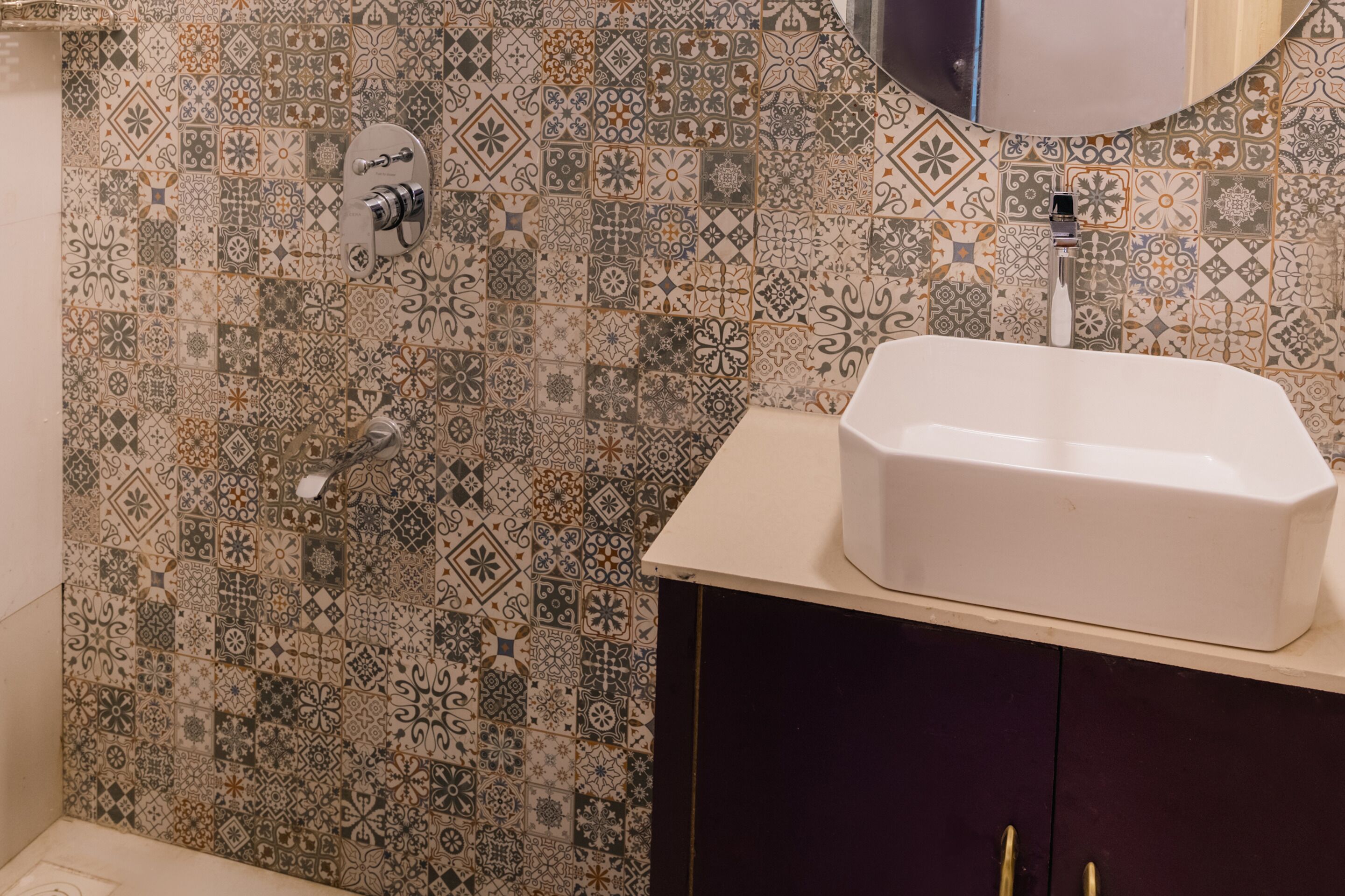 A bathroom with a patterned tile backsplash, a white sink, and a dark cabinet.