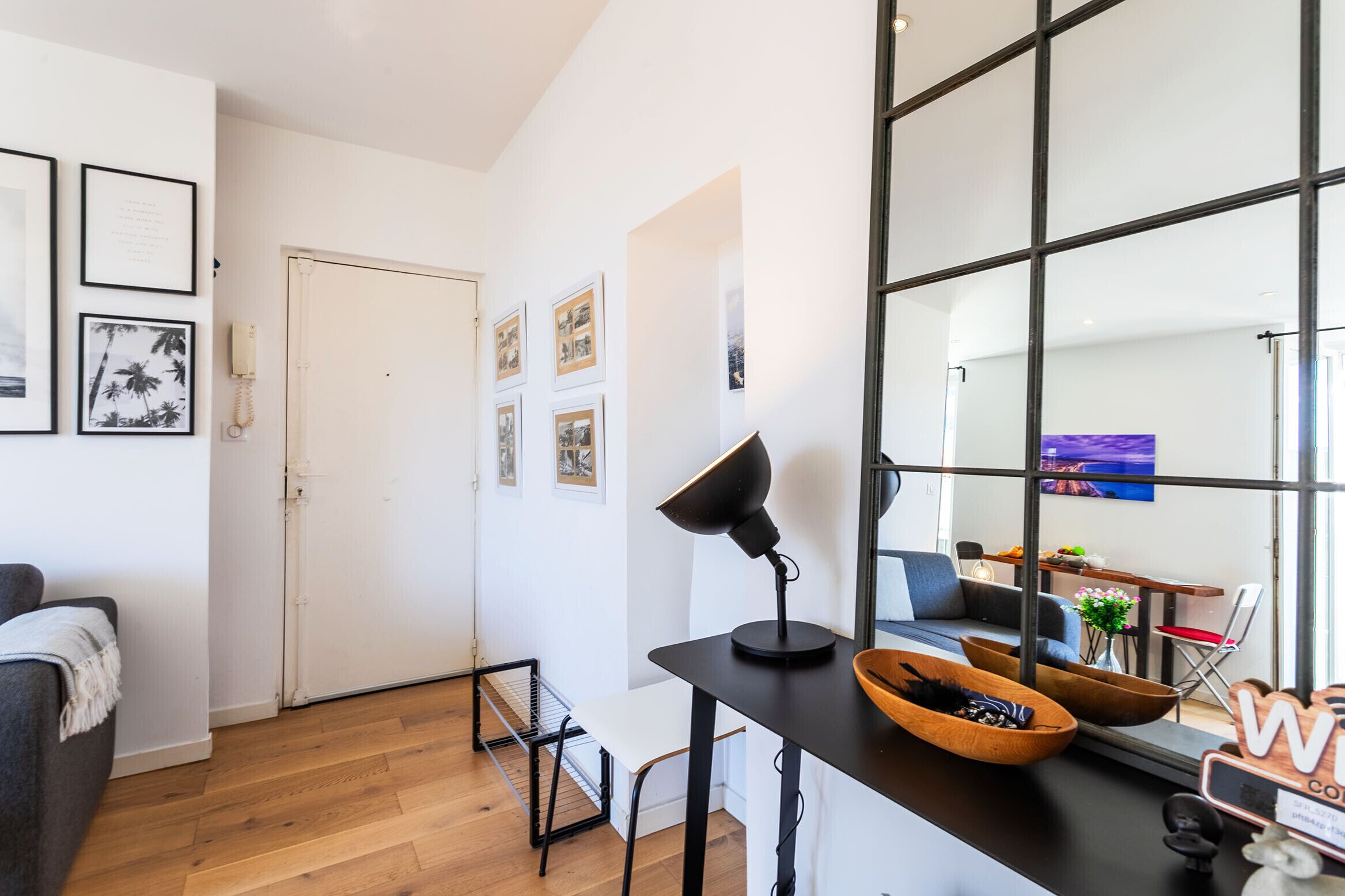 A modern living room with a sofa, a table with a lamp, and a large window.