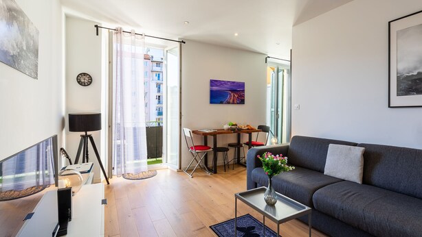 A modern living room with a sofa, a coffee table, and a dining area with a table and chairs.