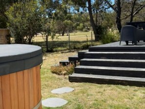 A hot tub with steps leading up to a seating area in a landscaped outdoor setting.