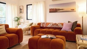 Un salon comprenant un canapé, un fauteuil, une table et une lampe.