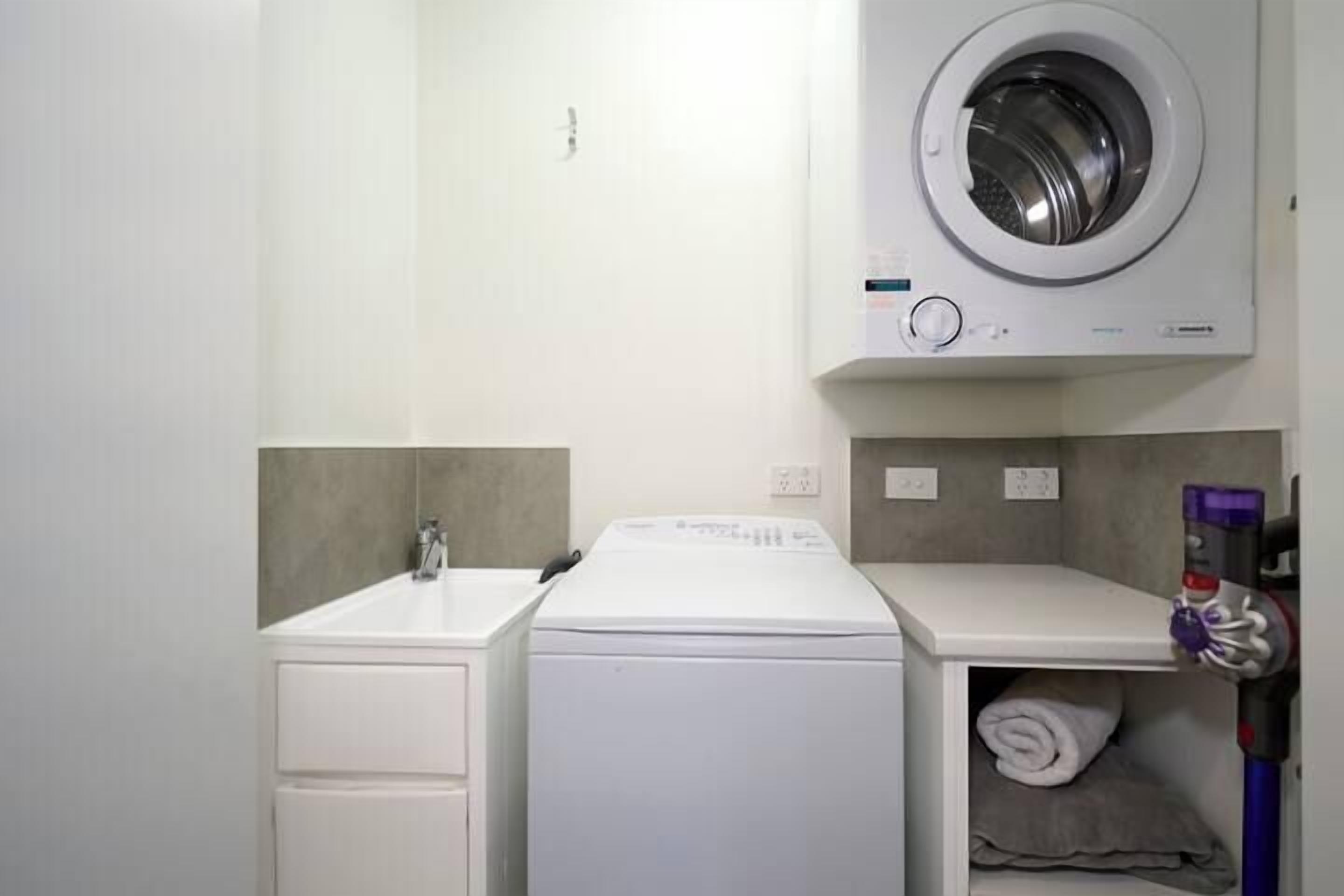 A compact laundry area with a washing machine, a dryer, and a sink.
